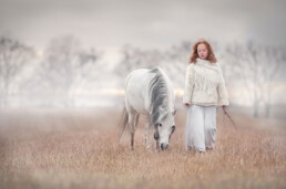 jente som går med en hest på engen