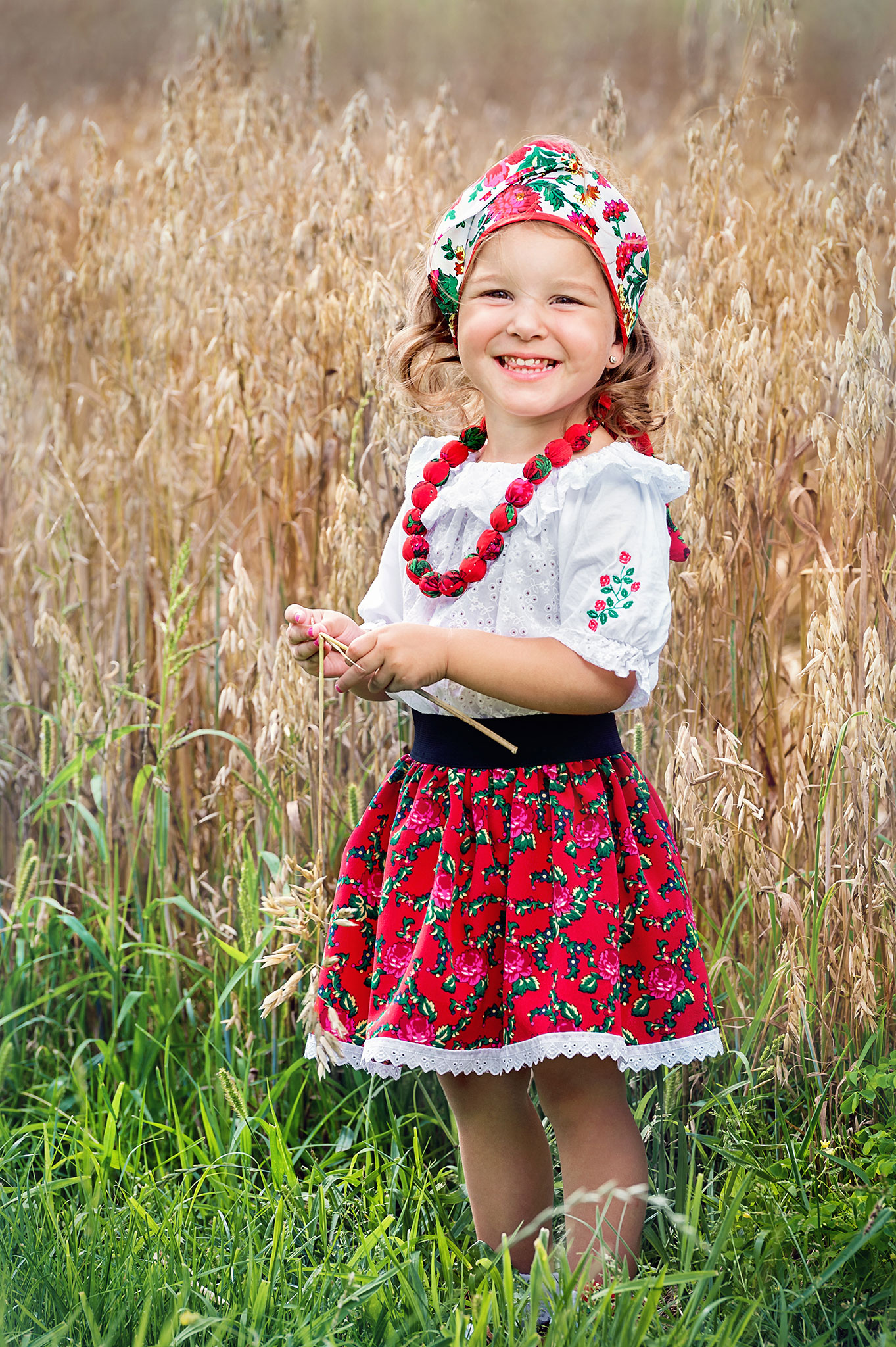 liten jente står og smiler i avlingen