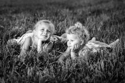 to små jenter ligger glade på enga