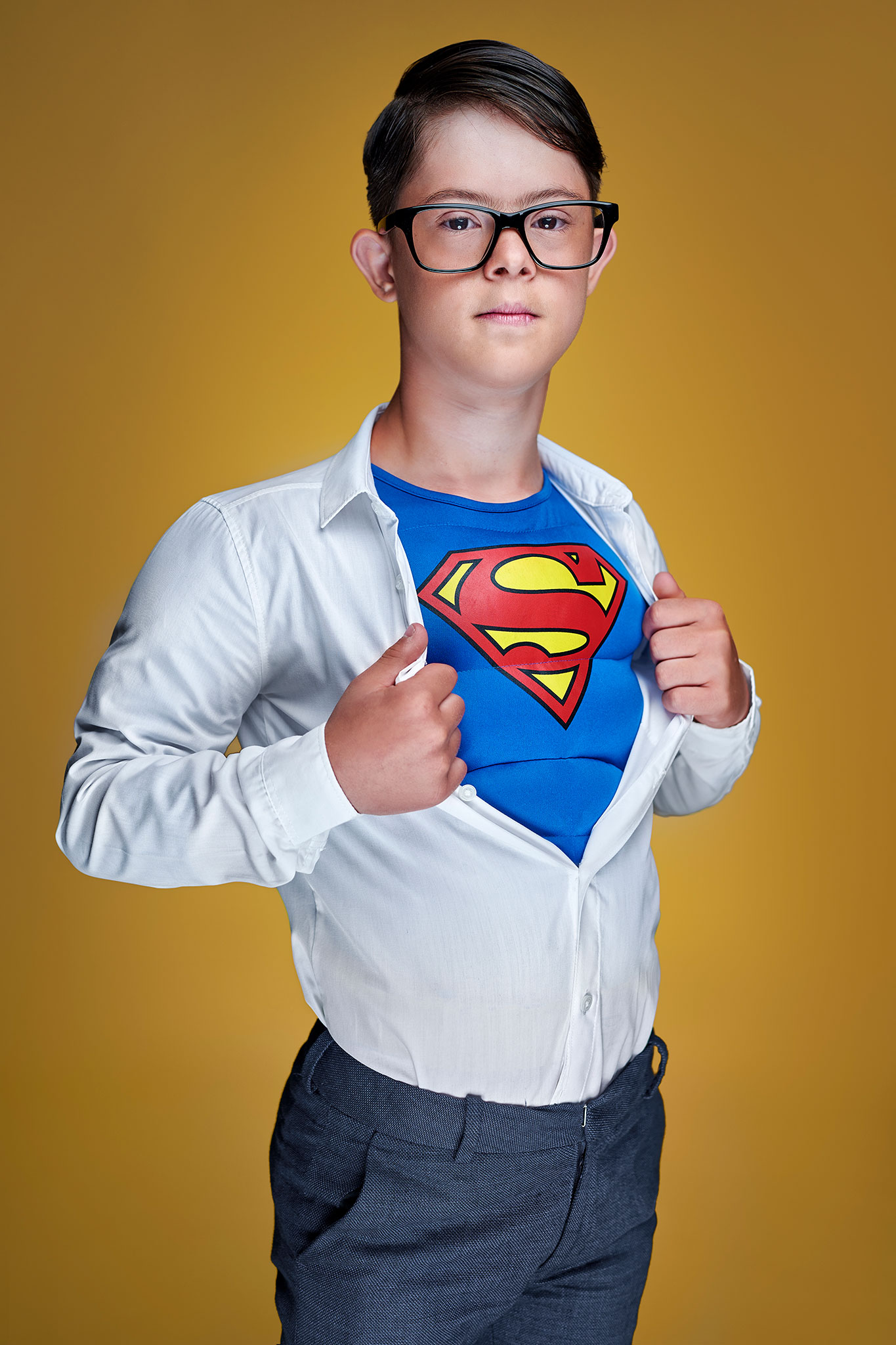 en liten gutt med downs syndrom står forkledd som en supermann