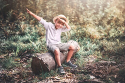 en liten gutt sitter på en stubbe i skogen og tuller