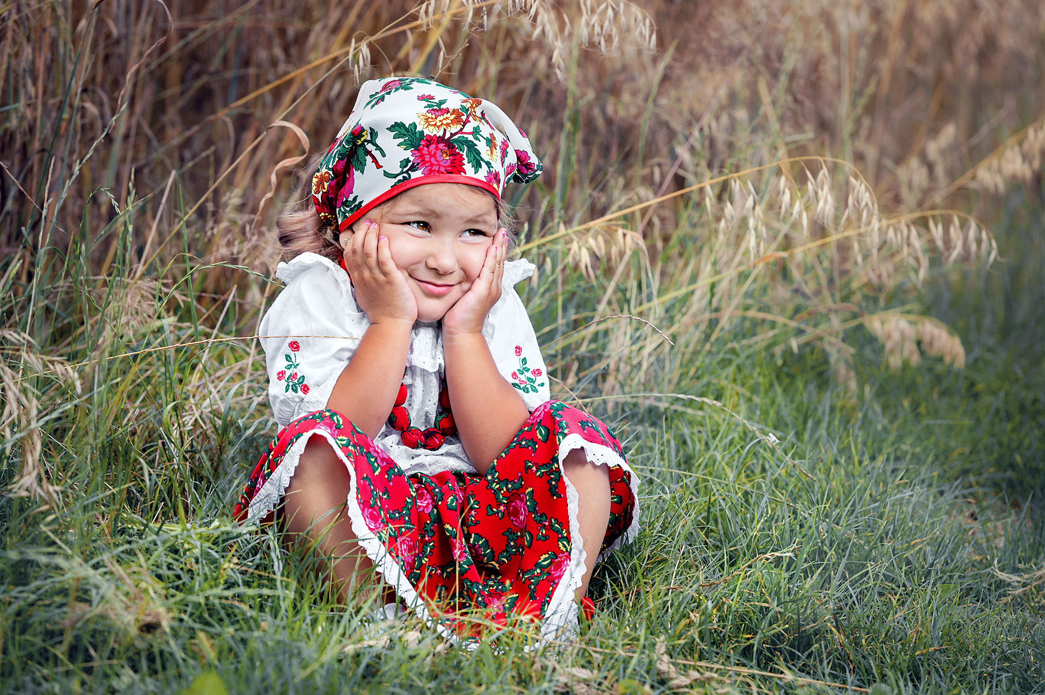 liten jente sitter og smiler i avlingen