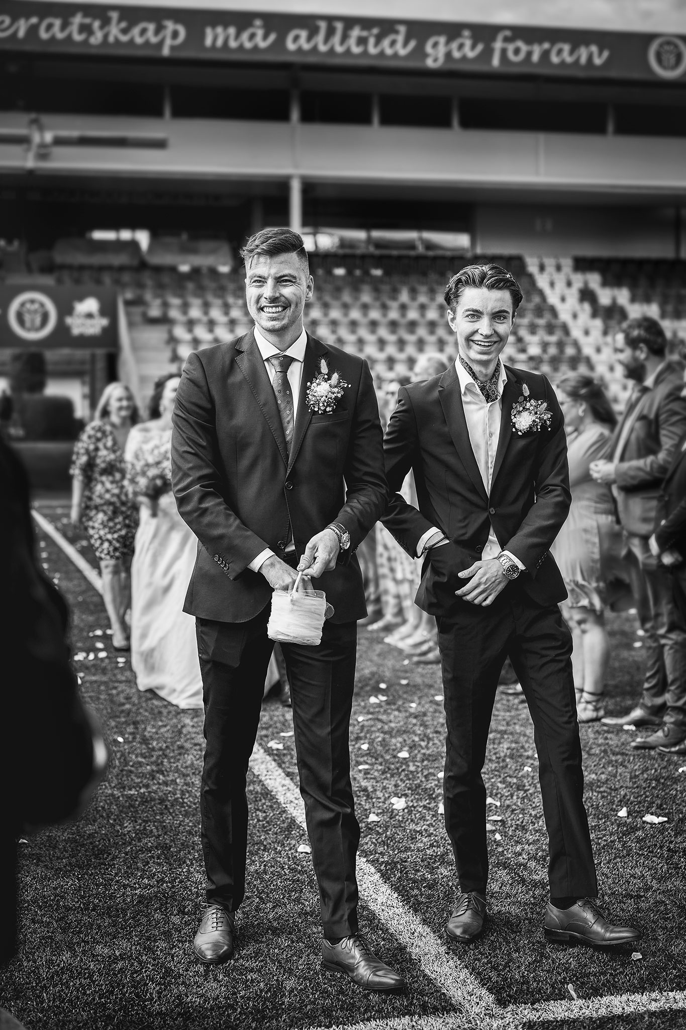 to menn i dress sprer ut blomsterblader på fotballstadion der bryllupet holdes