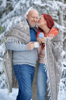 smilende kvinne og mann drikker kaffe og klemmer på en vinterdag