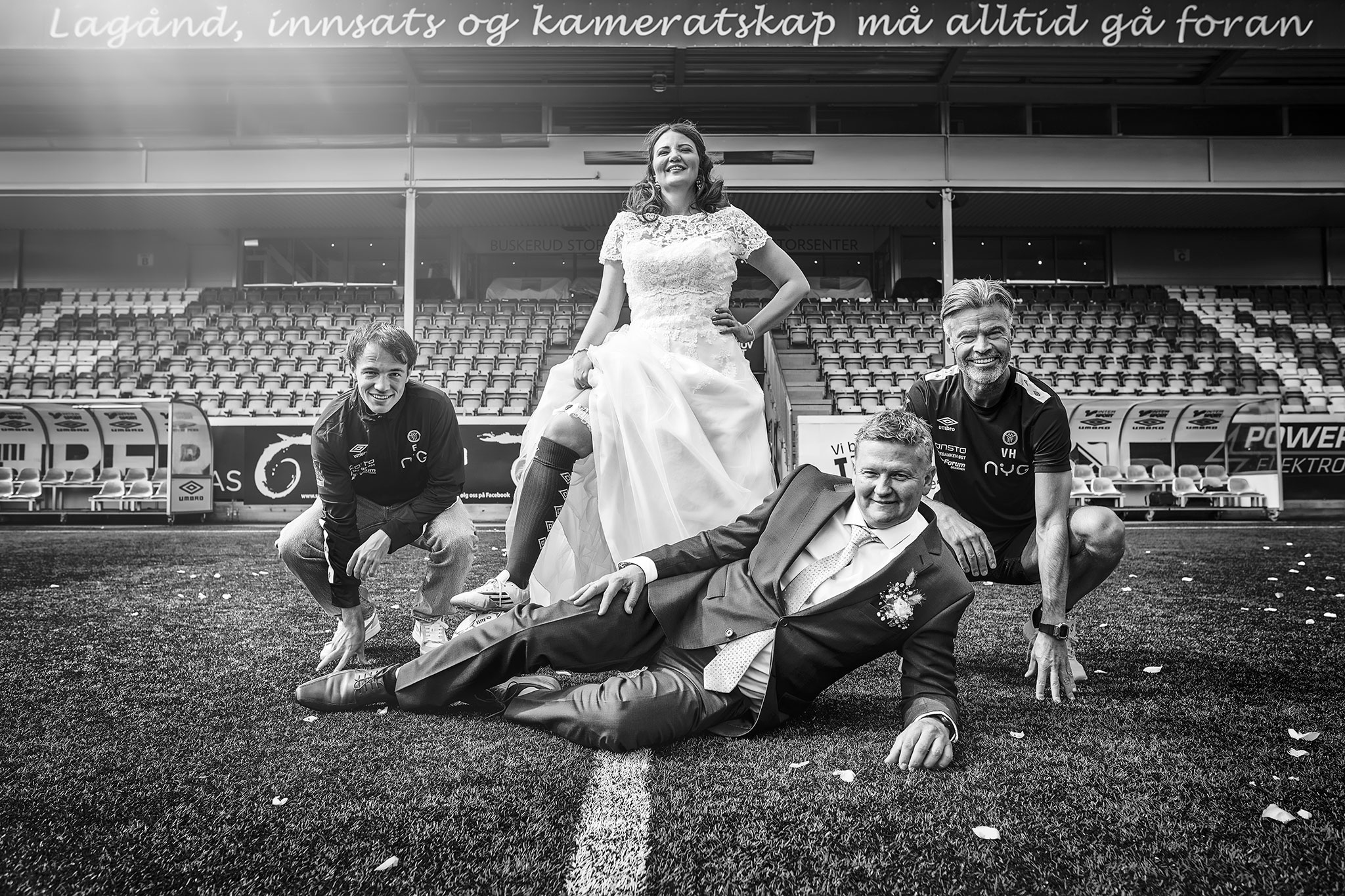 brudepar står på fotballbanen med to fotballspillere