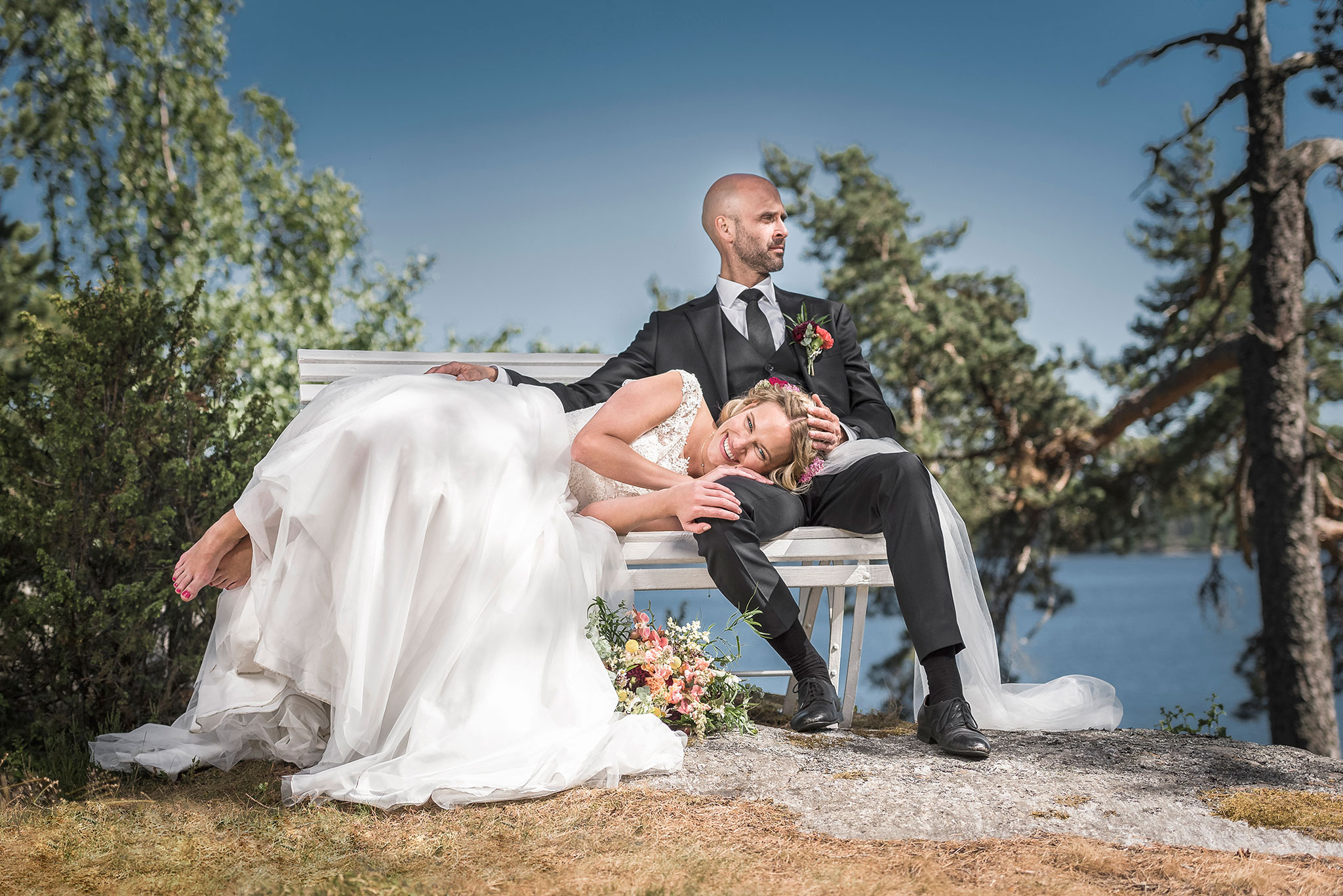 brudepar tuller rundt på en benk på bryllupsdagen