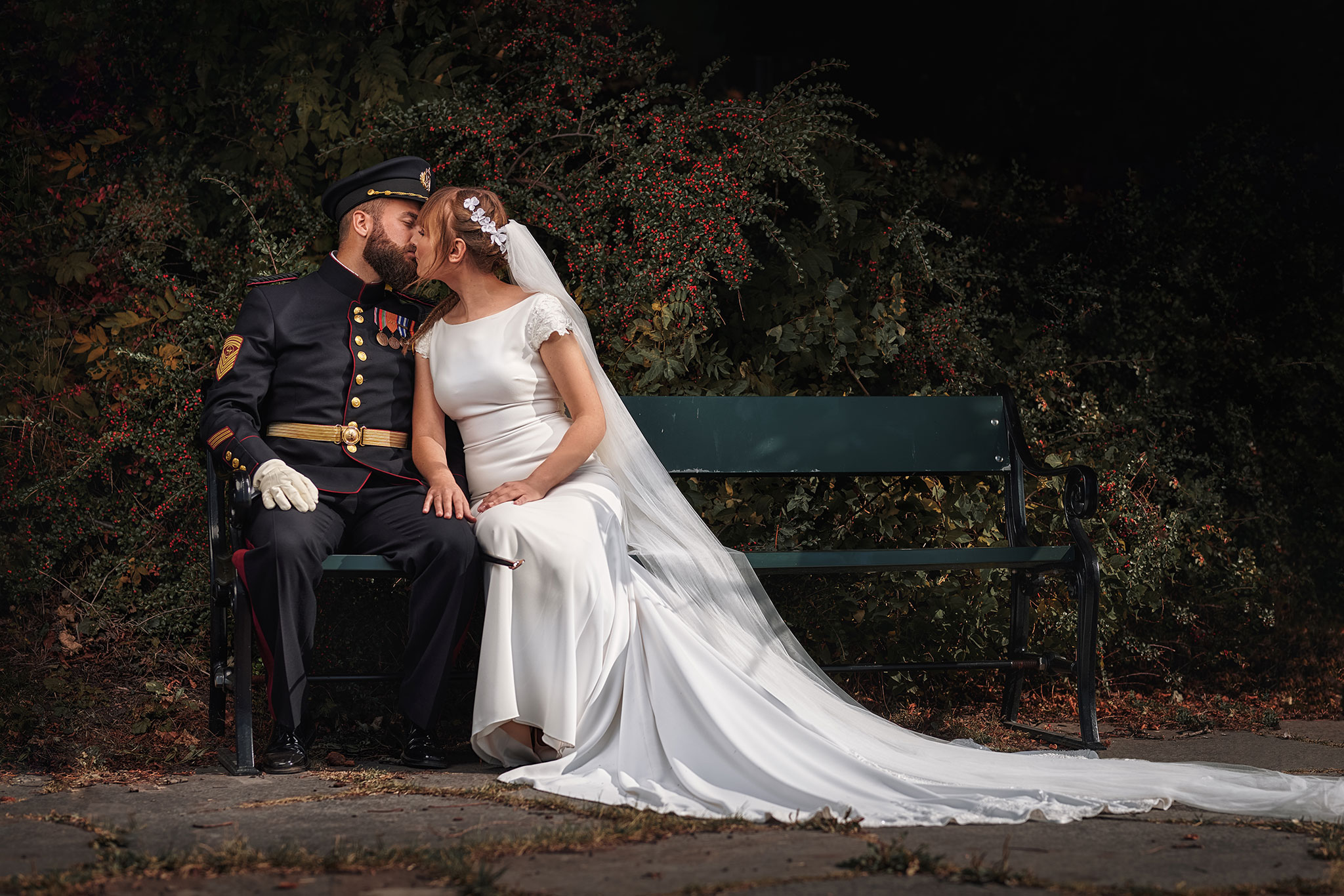 brudepar kysser på bryllupsdagen mens de sitter på en benk
