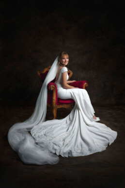 vakker brud sitter på tronen i en brudekjole med et langt slør