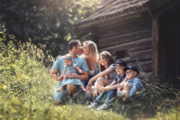 lykkelig familie som sitter ved siden av den gamle låven der foreldrene kysser