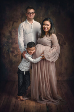 smilende familie venter på fødselen av babyen og poserer til familiebilder