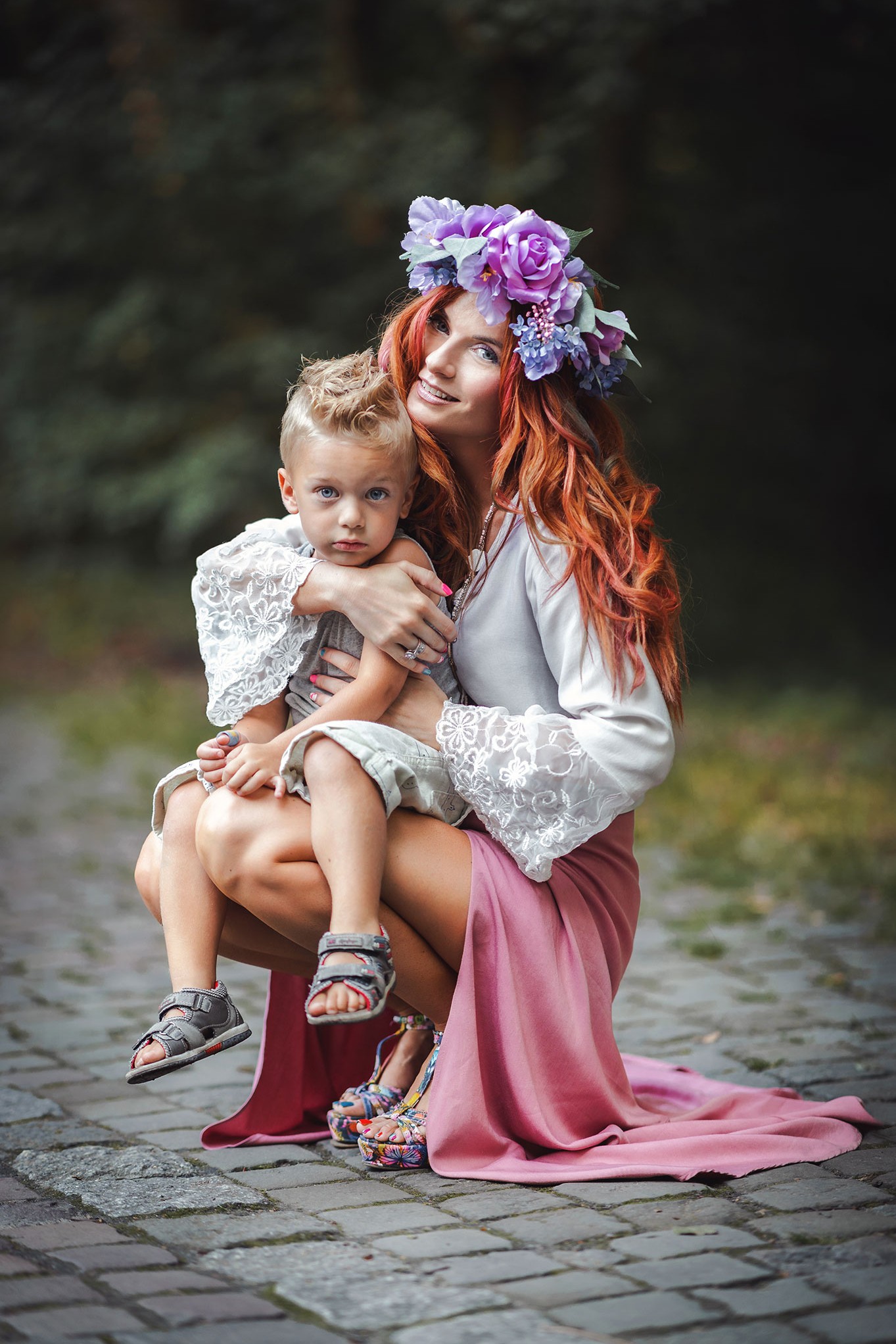 en rødhåret kvinne med en krans på hodet klemmer sønnen hennes