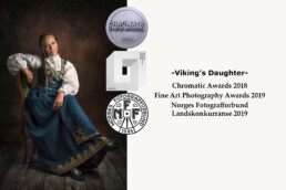 smilende jente i bunad sitter på en stol i et fotostudio