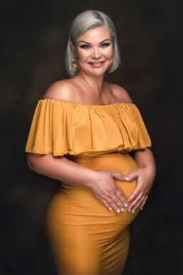 gravid blond kvinne viser et hjertetegn på magen