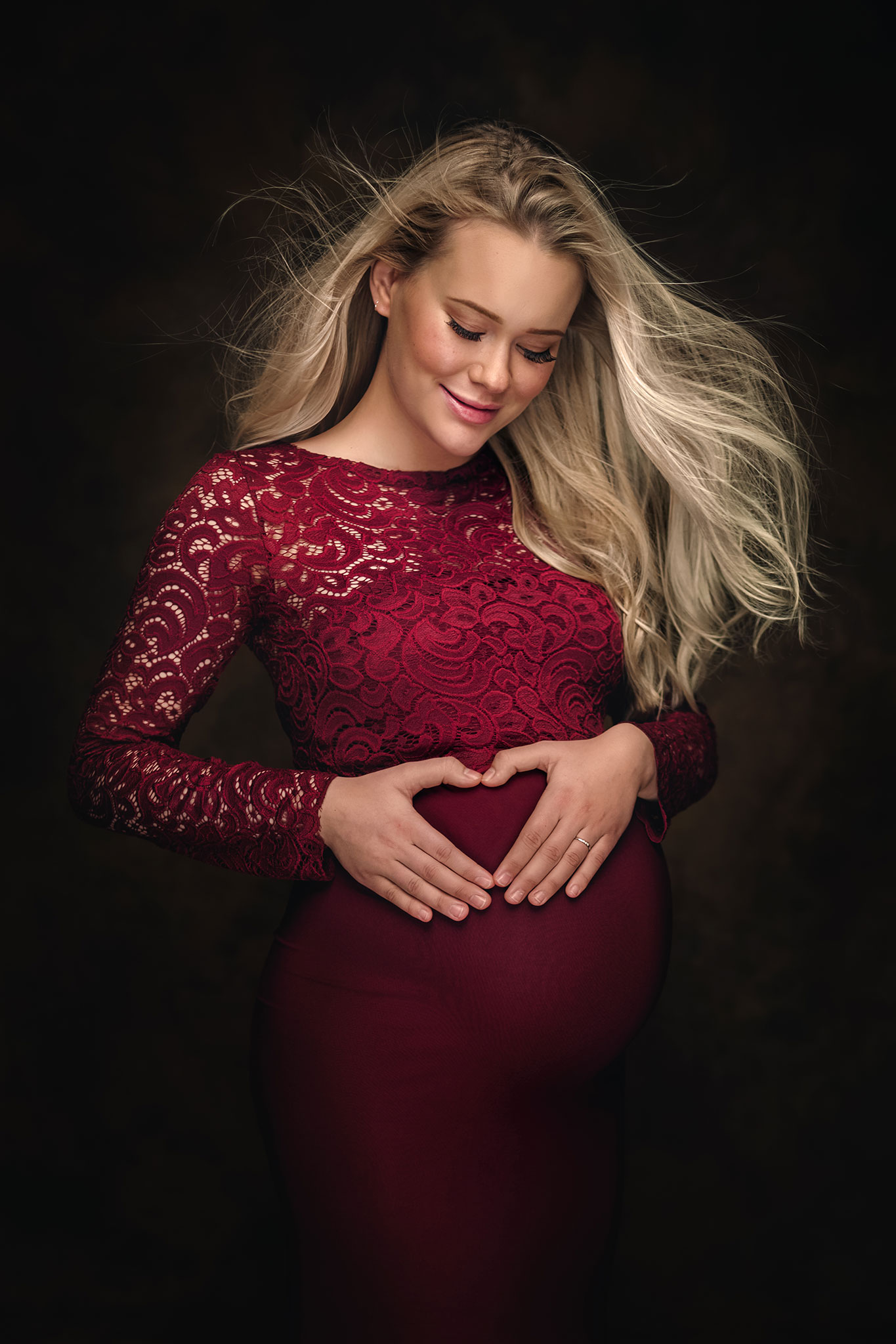 gravid blond kvinne viser et hjertetegn på magen