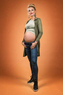 gravid kvinne poserer for bilder på en gul bakgrunn