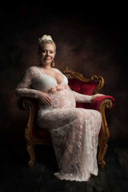 gravid kvinne i en hvit kjole sitter på en vakker gammel lenestol