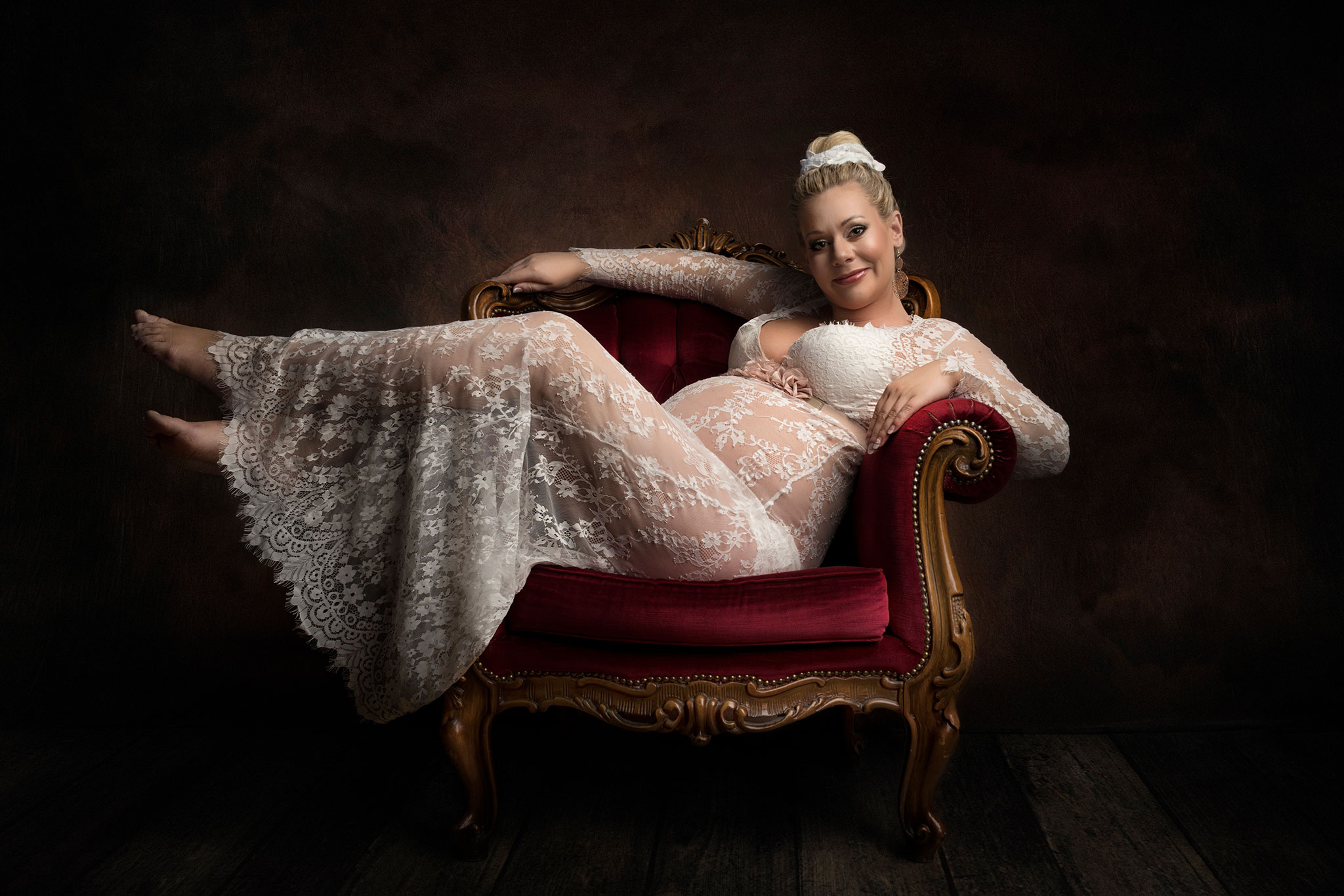 en gravid kvinne i en hvit kjole ligger på en vakker gammel lenestol