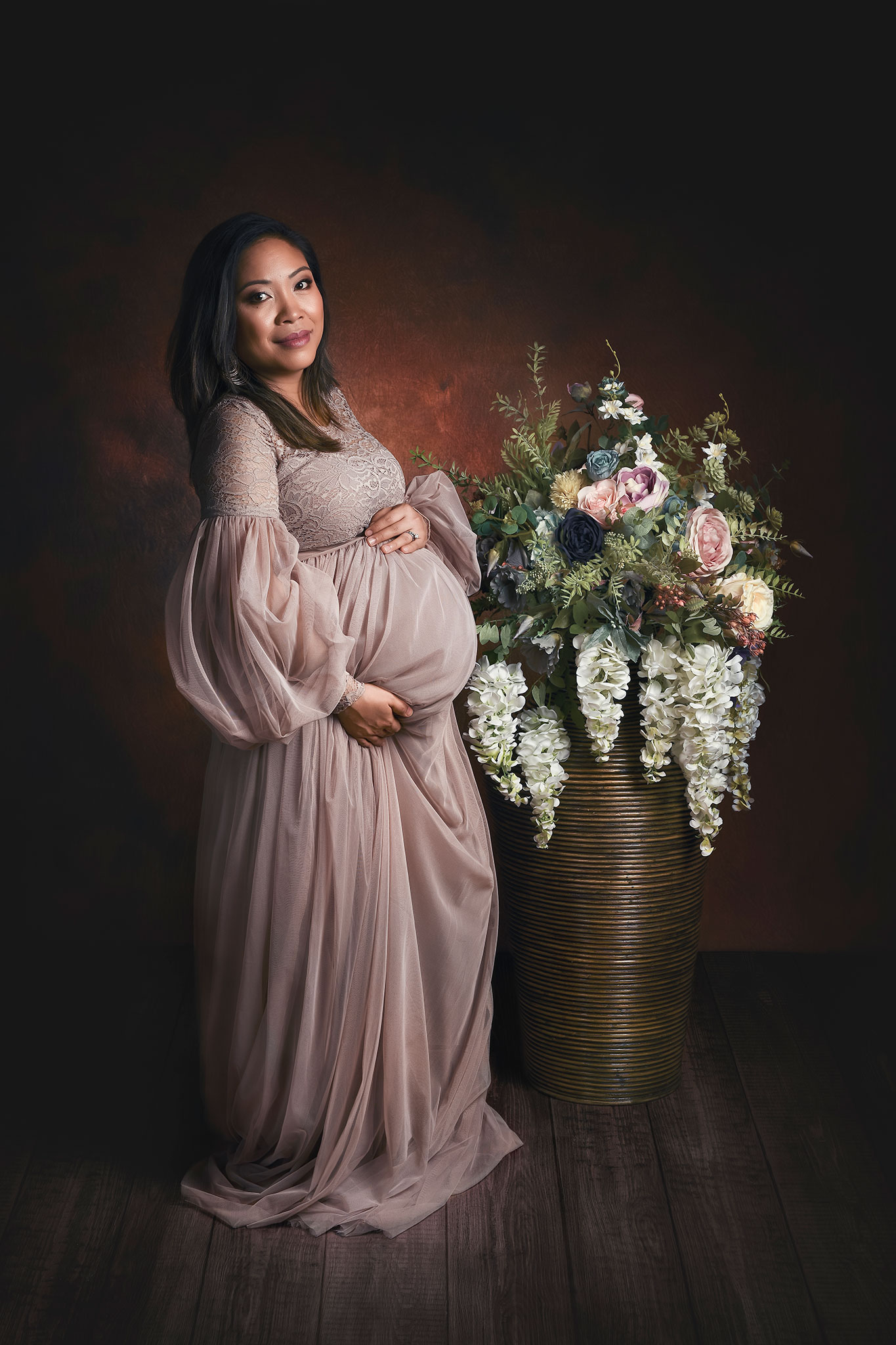 gravid kvinne poserer til gravidbilder med en bukett blomster
