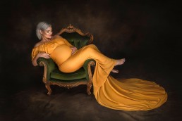 gravid kvinne poserer i studio for bilder i en elegant gul kjole