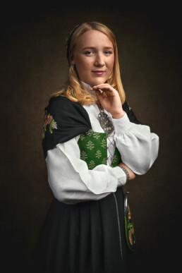 en jente med blondt hår som feirer konfirmasjon, stiller opp for bilder i et fotostudio