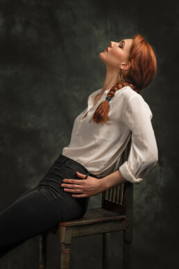 rødhåret kvinne sitter på en stol med lukkede øyne og drømmer