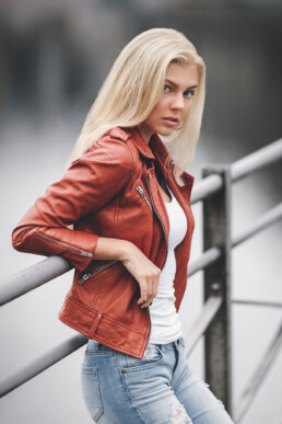 en blond jente i rød jakke lener seg mot rekkverket