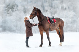 jente som står med en hest i vinter