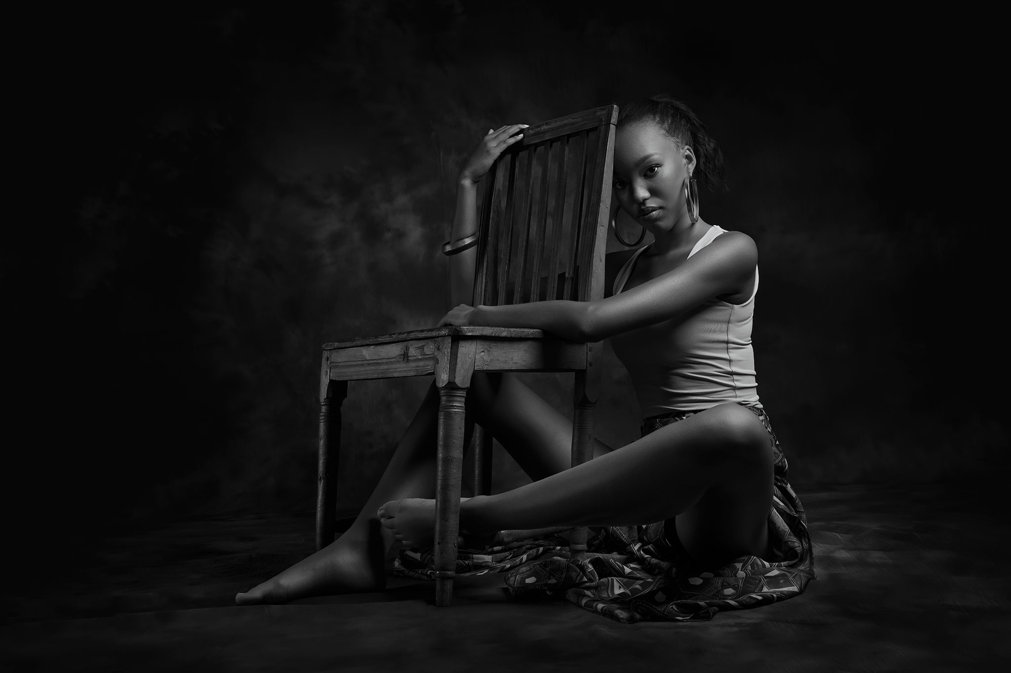 en mørkhudet jente sitter på gulvet ved siden av stolen